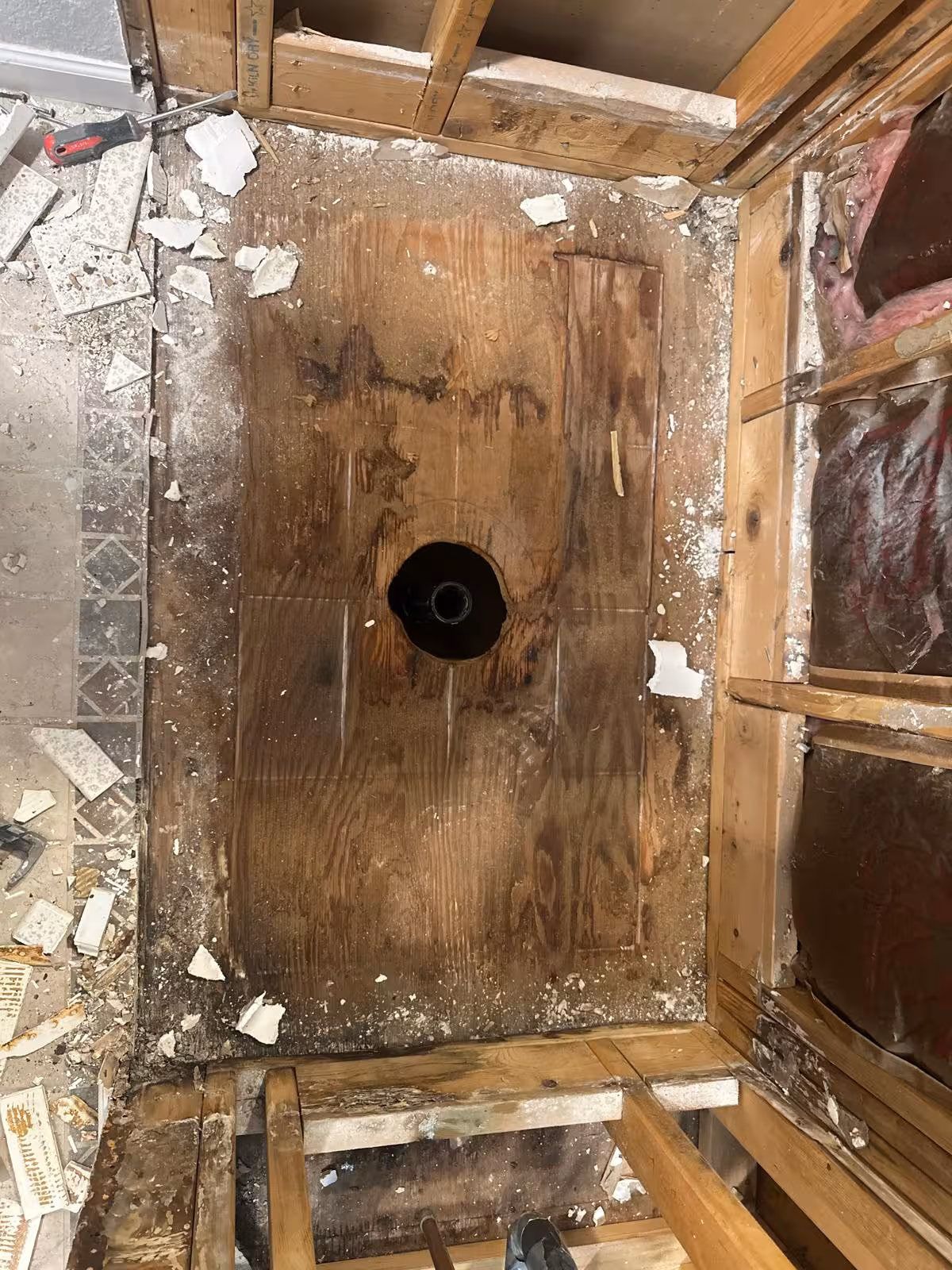 Removed shower base with water-damaged subfloor exposed during Arvada shower reconstruction