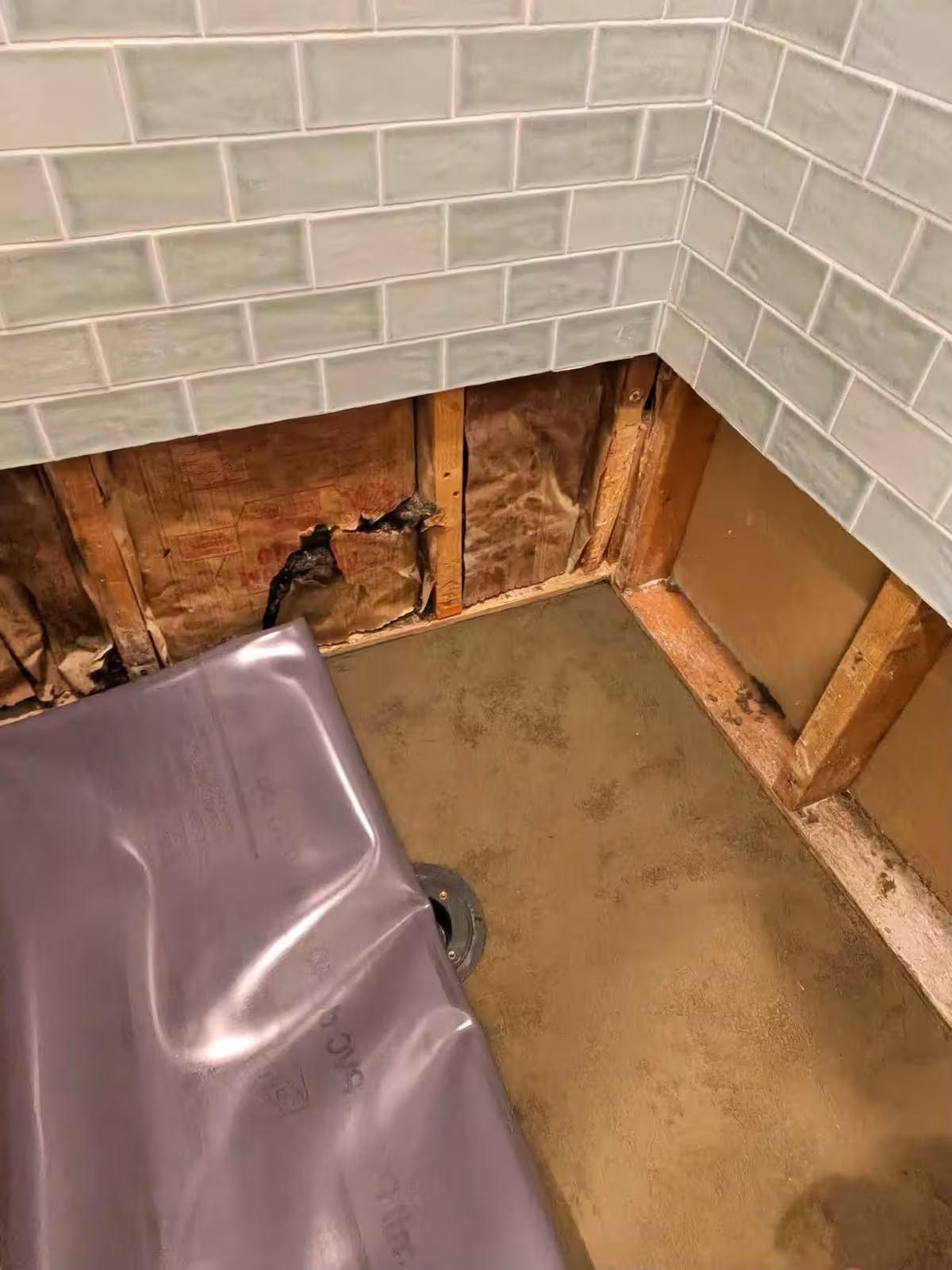 Exposed shower pan liner installation with visible framing Denver