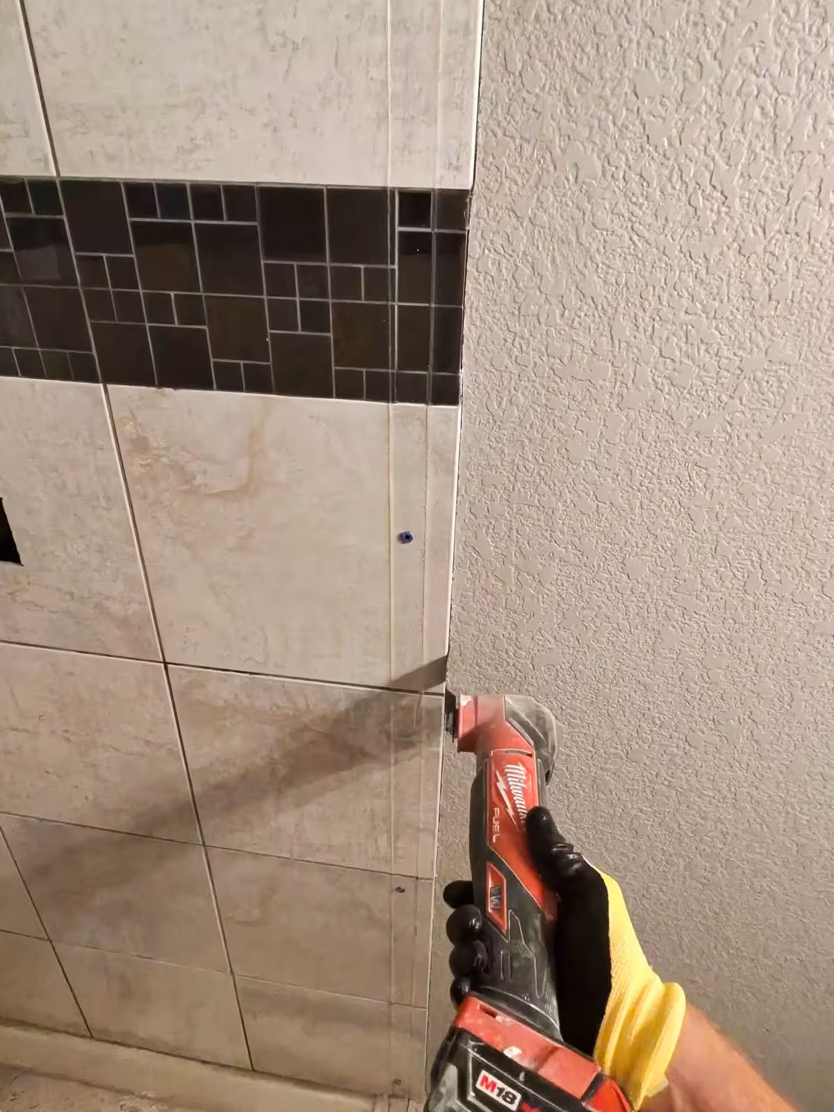 Cutting beige tile with Milwaukee oscillating multi-tool during removal