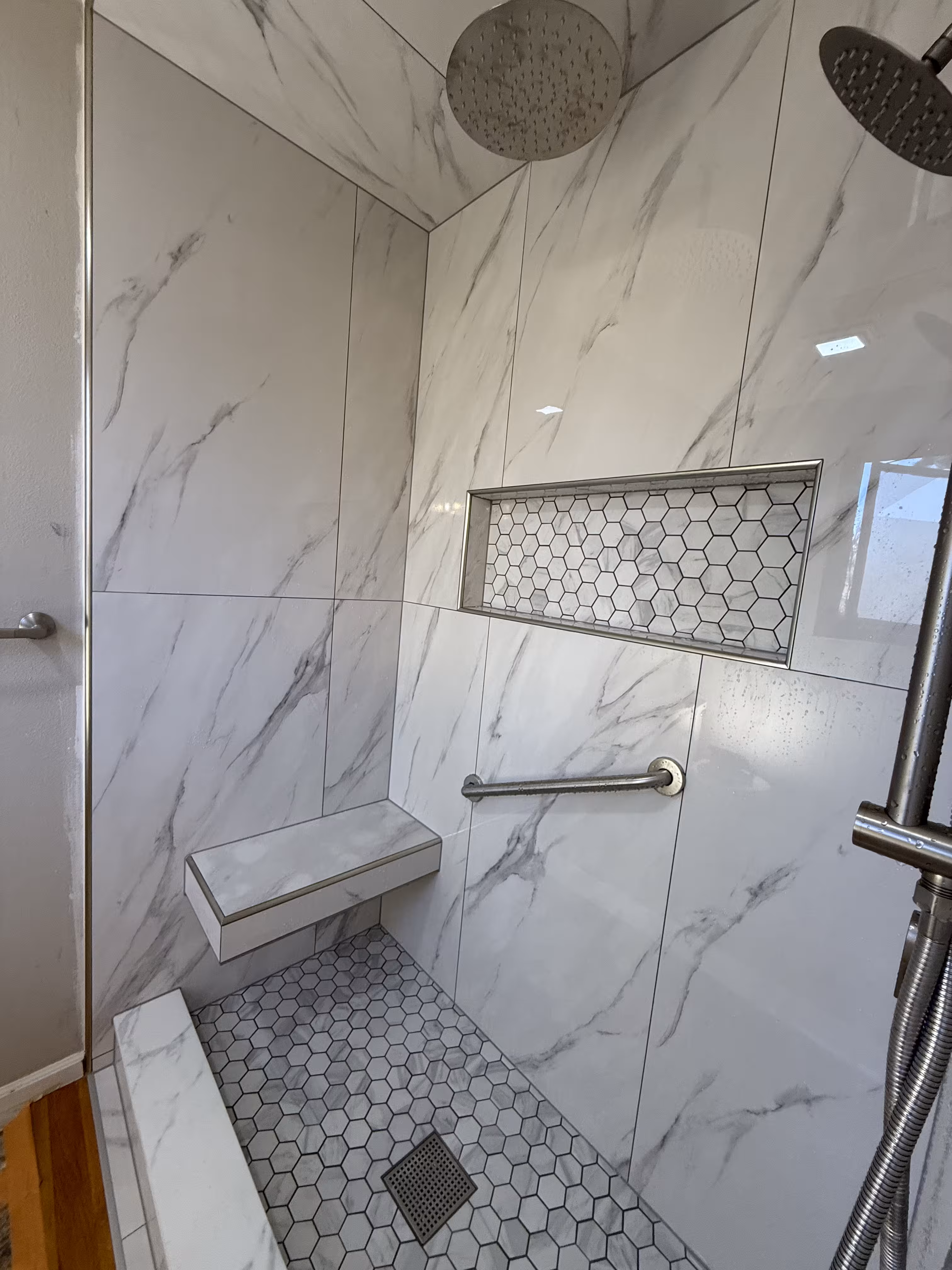 Finished marble-look shower with floating bench and large-format tile in Highlands Ranch