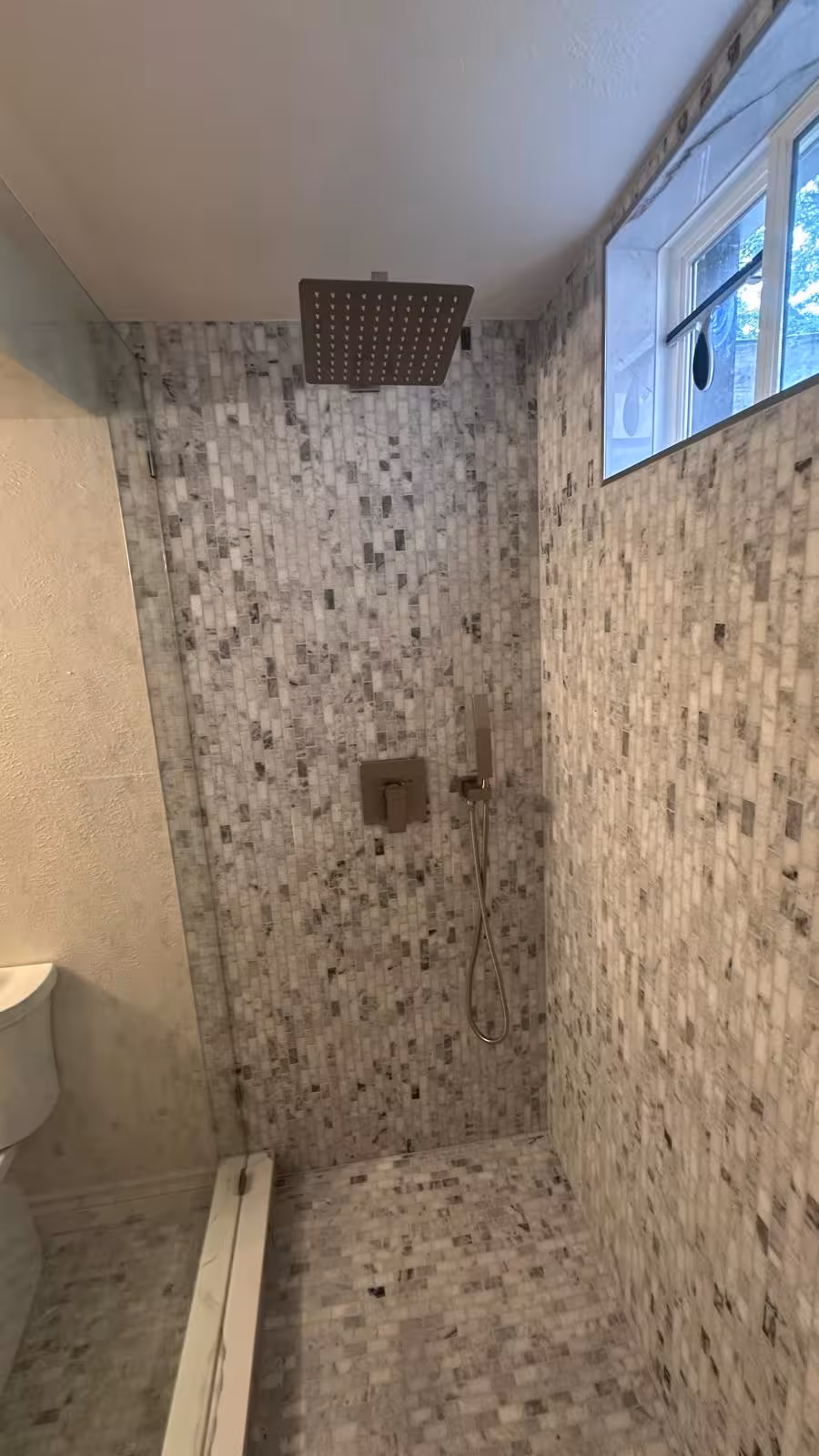 Modern basement shower with overhead rainfall head and marble mosaic tile Littleton