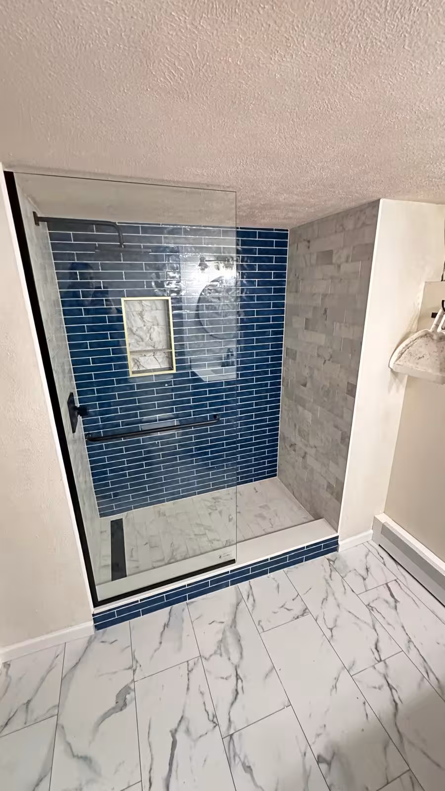 Completed basement bathroom remodel with new LVP flooring and modern walk-in shower Aurora Colorado