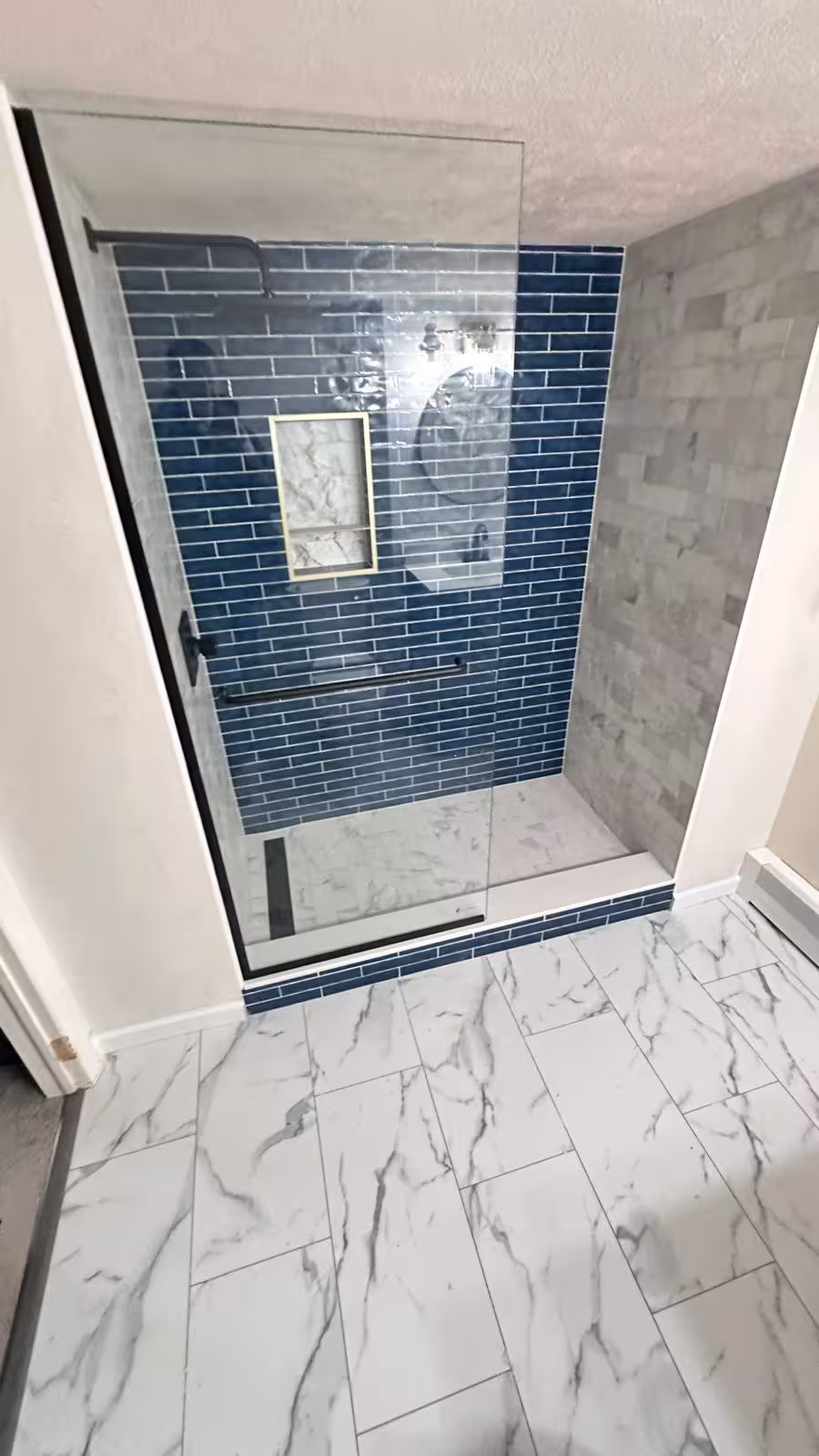 Walk-in shower entrance with frameless glass partition after basement bathroom conversion