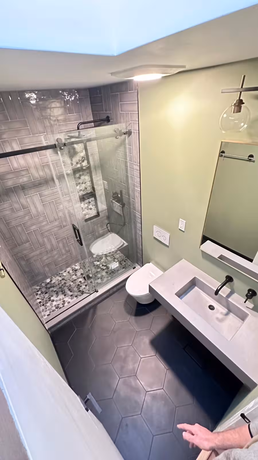 Designer bathroom with skylight flooding space with natural light herringbone walls visible
