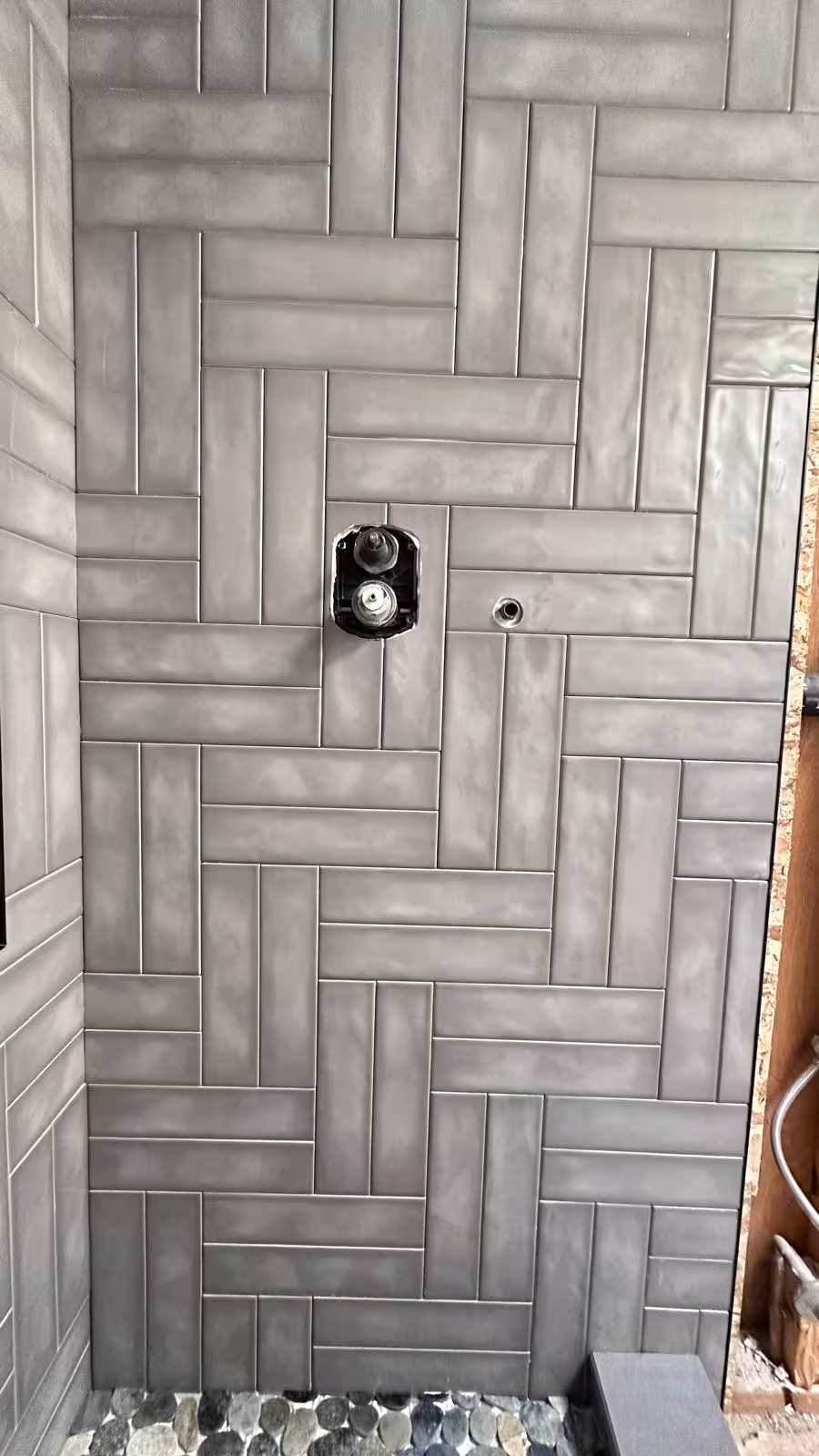 Gray subway tile installed in herringbone pattern with vertical storage niche detail