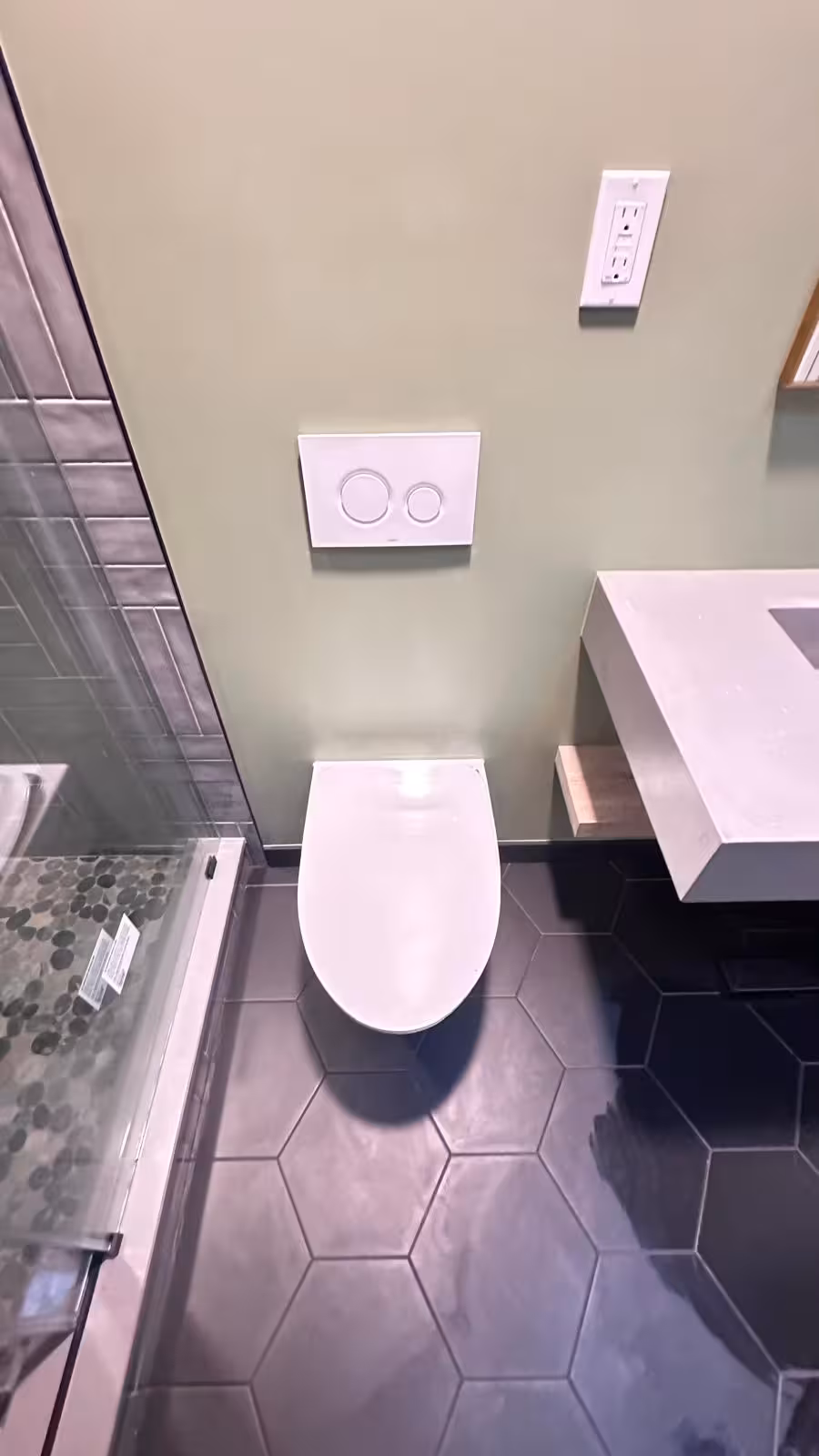 Wall-mounted TOTO toilet in completed Littleton bathroom remodel with modern black fixtures