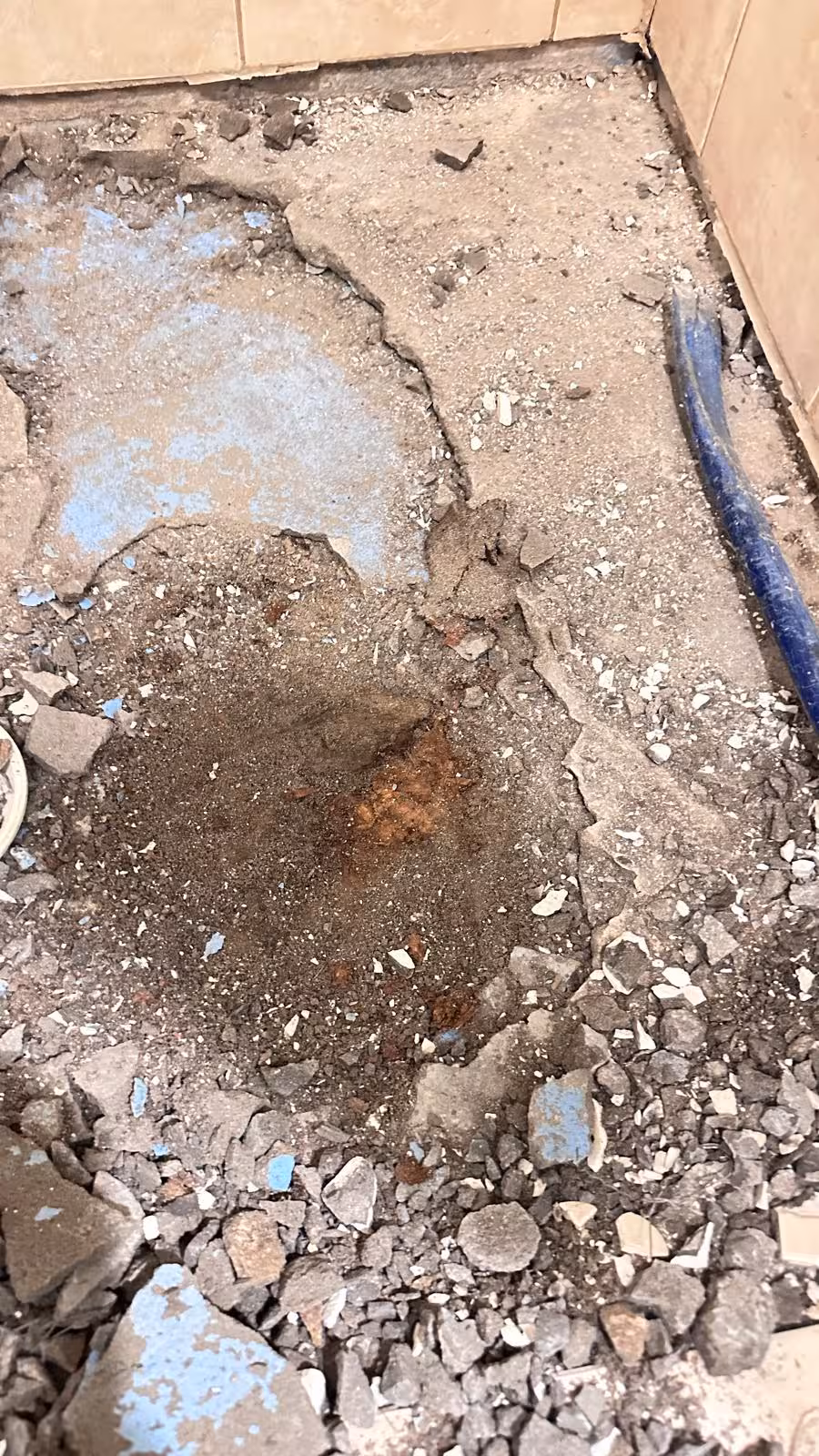 Close-up of failed shower pan showing crumbling concrete mortar bed during demolition Elizabeth CO