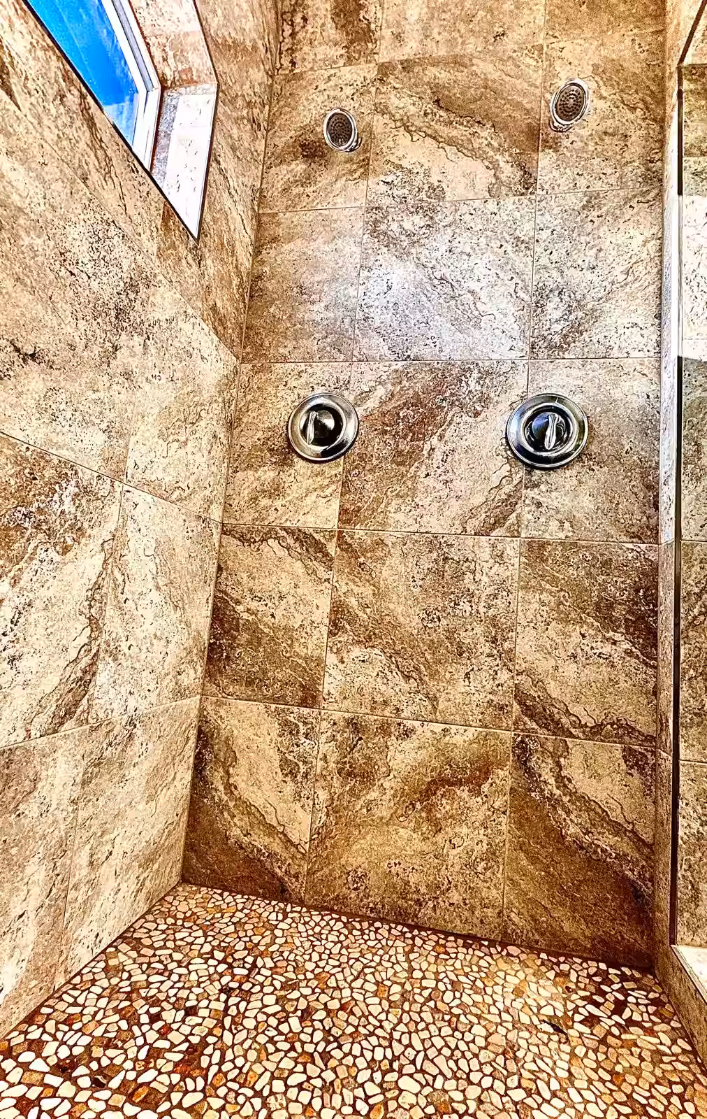 Luxury shower renovation complete with pebble stone floor and premium finishes