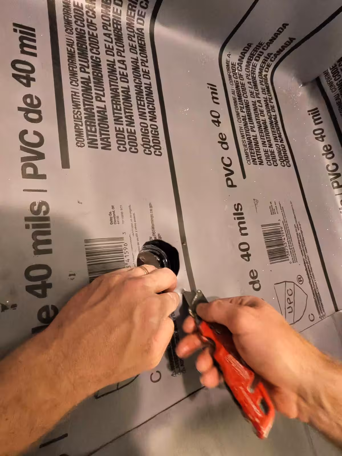 Cutting PVC shower pan liner around drain opening during installation Denver