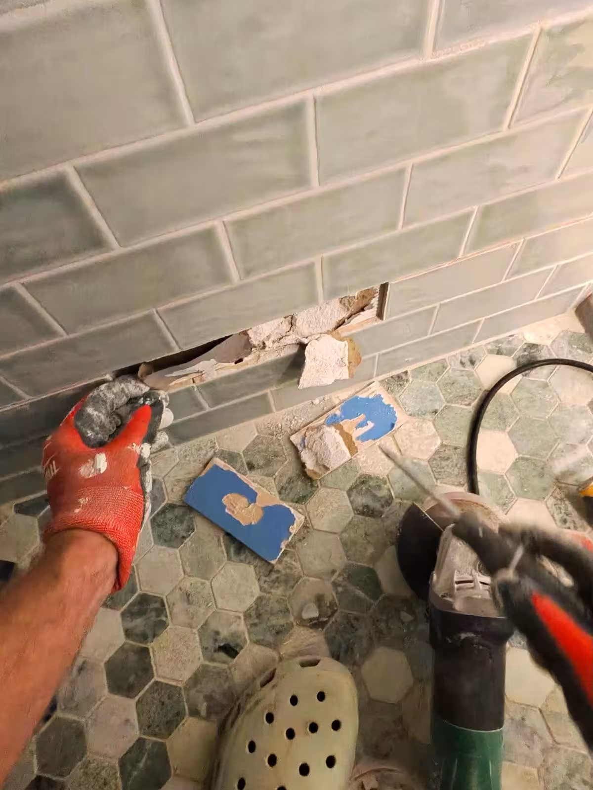 Removing damaged subway tile wall during shower demolition Denver
