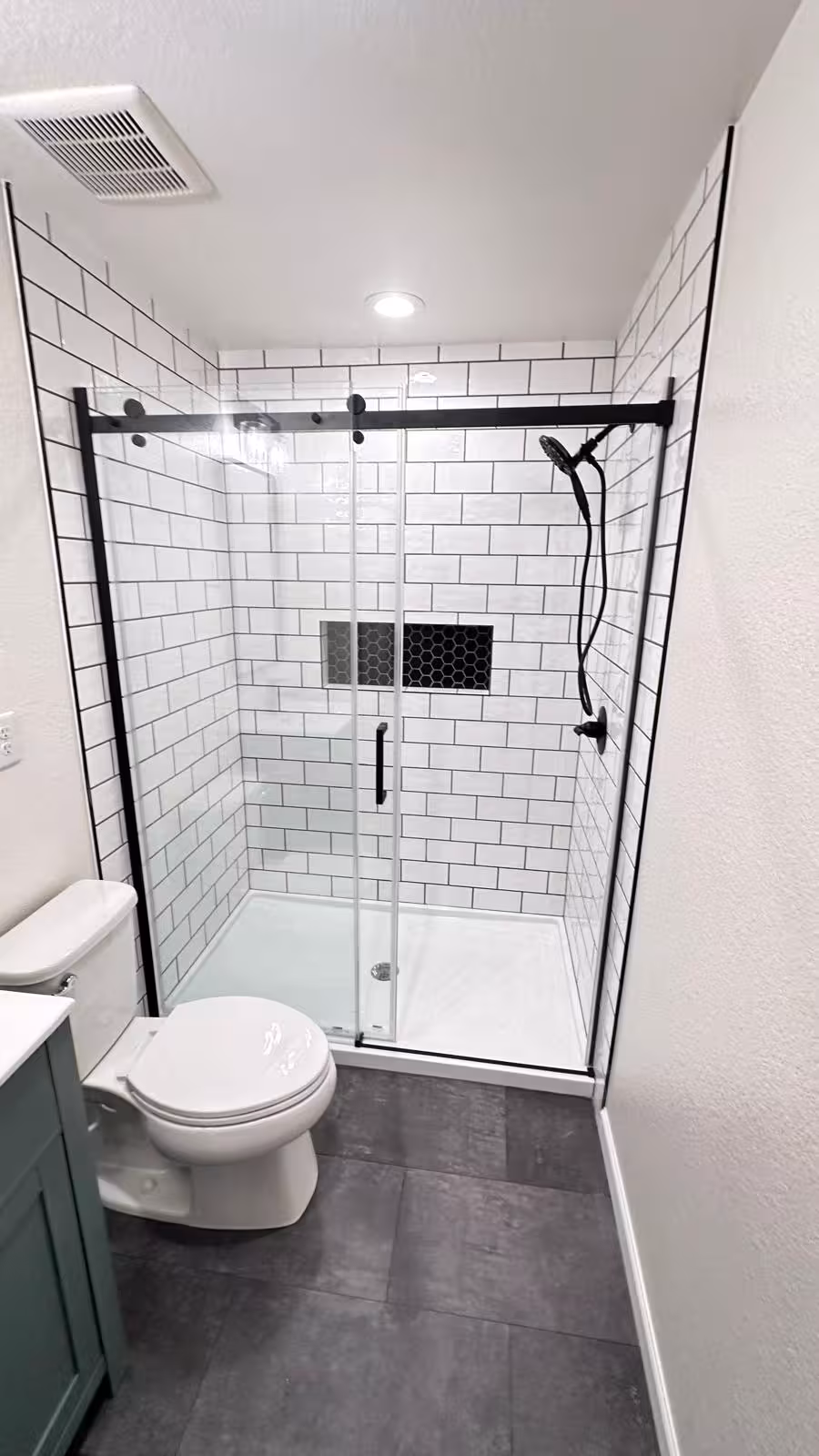 Modern tile shower installation with black-framed glass door front view