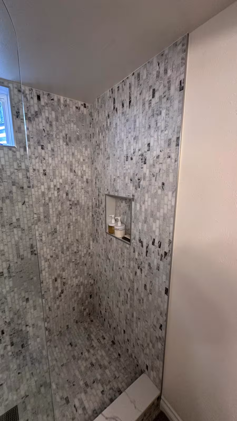 Marble mosaic tile shower niche with frameless glass door Littleton basement